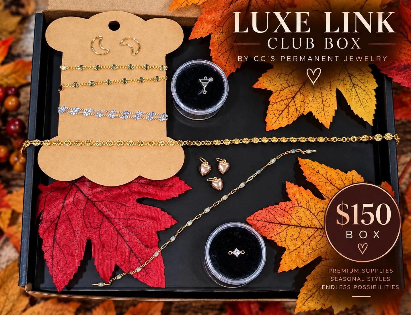 The $150 Luxe Link Club box: gold and silver flower chains on a kraft card, heart charms, moon connectors, a cocktail charm and a crystal connector in display cases.